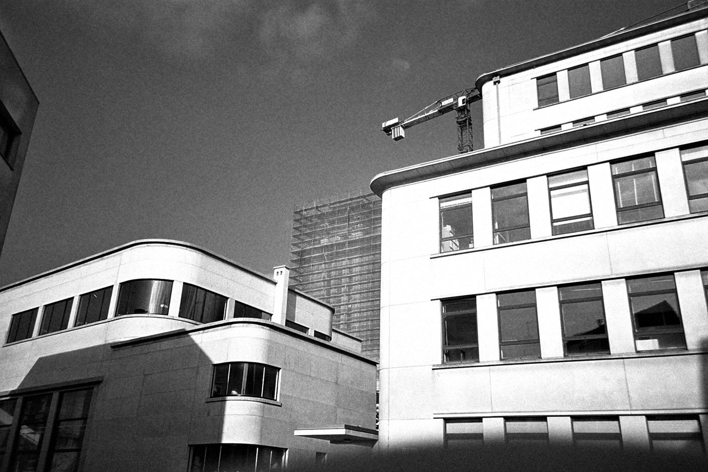 Witte modernistische gebouwen met afgeronde hoeken, een bouwkraan en een toren in de steigers