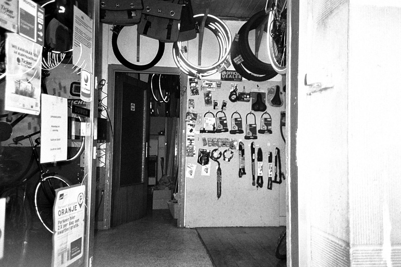 Doorkijk in een fietsenwinkel met banden aan het plafond en sloten aan de muur